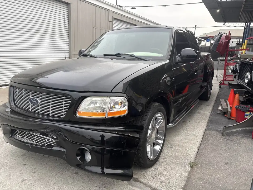 Before: left front of the 2000 Ford F150 Harley-Davidson Edition showing bumper and fender damage