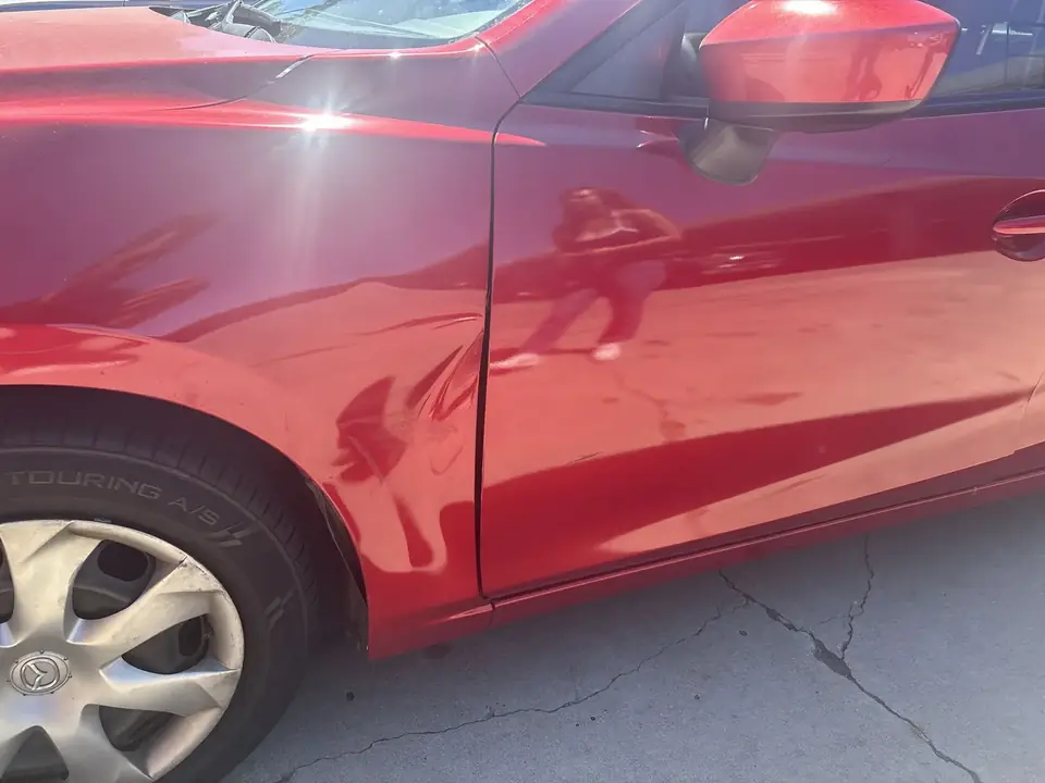 Before: close-up of the dented left fender and left front door edge on a 2014 Mazda 3 Sport
