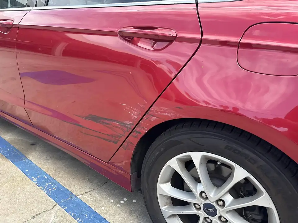 Before: damaged left rear door and quarter panel on a red 2020 Ford Fusion