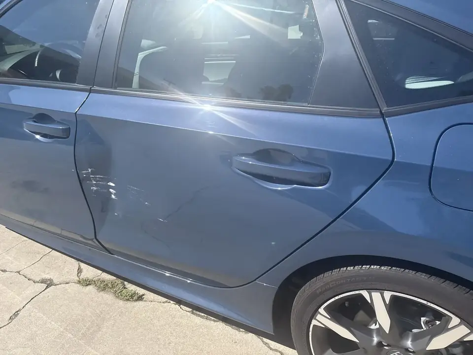 Before: close-up of dented left rear door on a 2025 Honda Civic