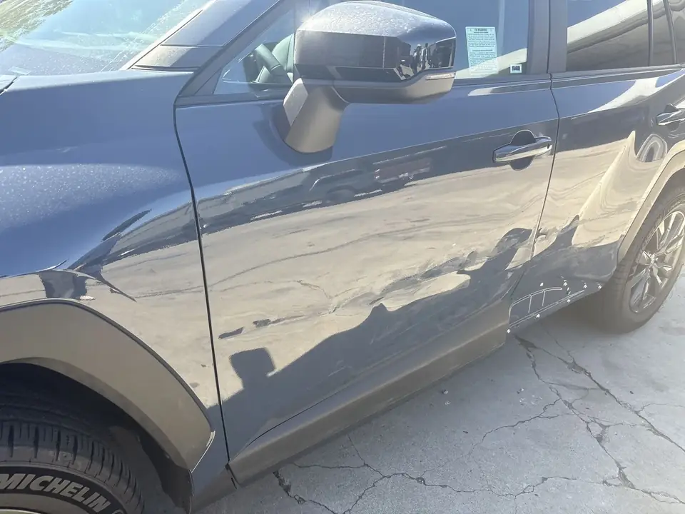 Before: close-up of the dented left front door and fender on a 2026 Toyota RAV4 XLE