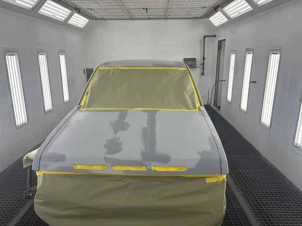 Pickup truck primed and masked for paint inside the brightly lit downdraft paint booth at Clairemont Collision in San Diego