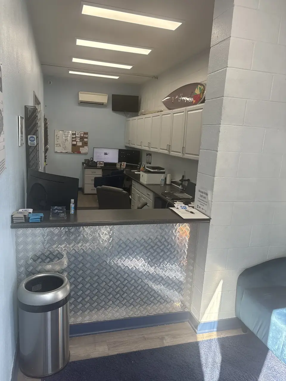 Clairemont Collision front office and service counter in Kearny Mesa, with the shop's custom painted surfboard on the wall