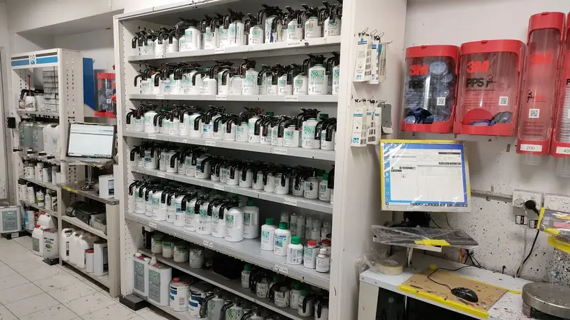 Paint mixing room at Clairemont Collision in San Diego, with shelves of tinting toner cans, a color formula computer screen and wall-mounted 3M dispensers